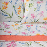 Dettaglio del completo letto con vivace stampa floreale, coppia di federe e lenzuolo sopra interamente stampato