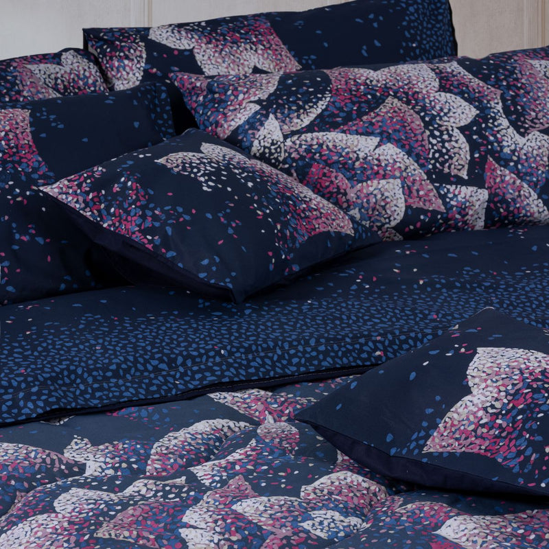 Dettaglio completo letto e cuscino arredo fondo blu notte con vivace stampa floreale astratta 