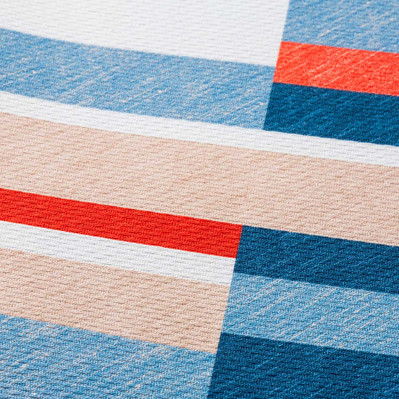 Dettaglio trama piquet del copriletto estivo in cotone con stampa a righe blu rosso e naturale